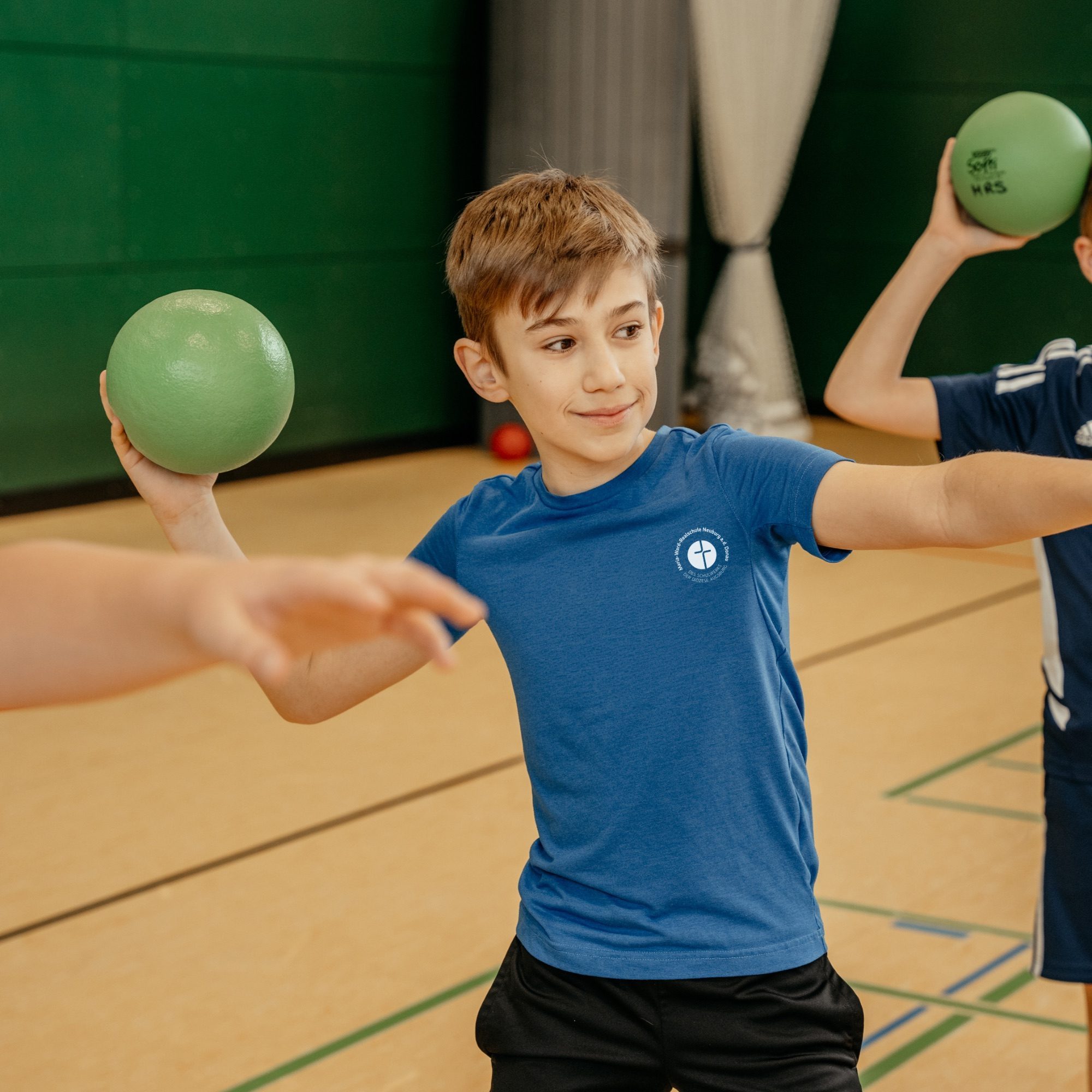 Schüler im blauen Schulsportshirt mit Logo der Maria-Ward-Realschule Neuburg in der Turnhalle