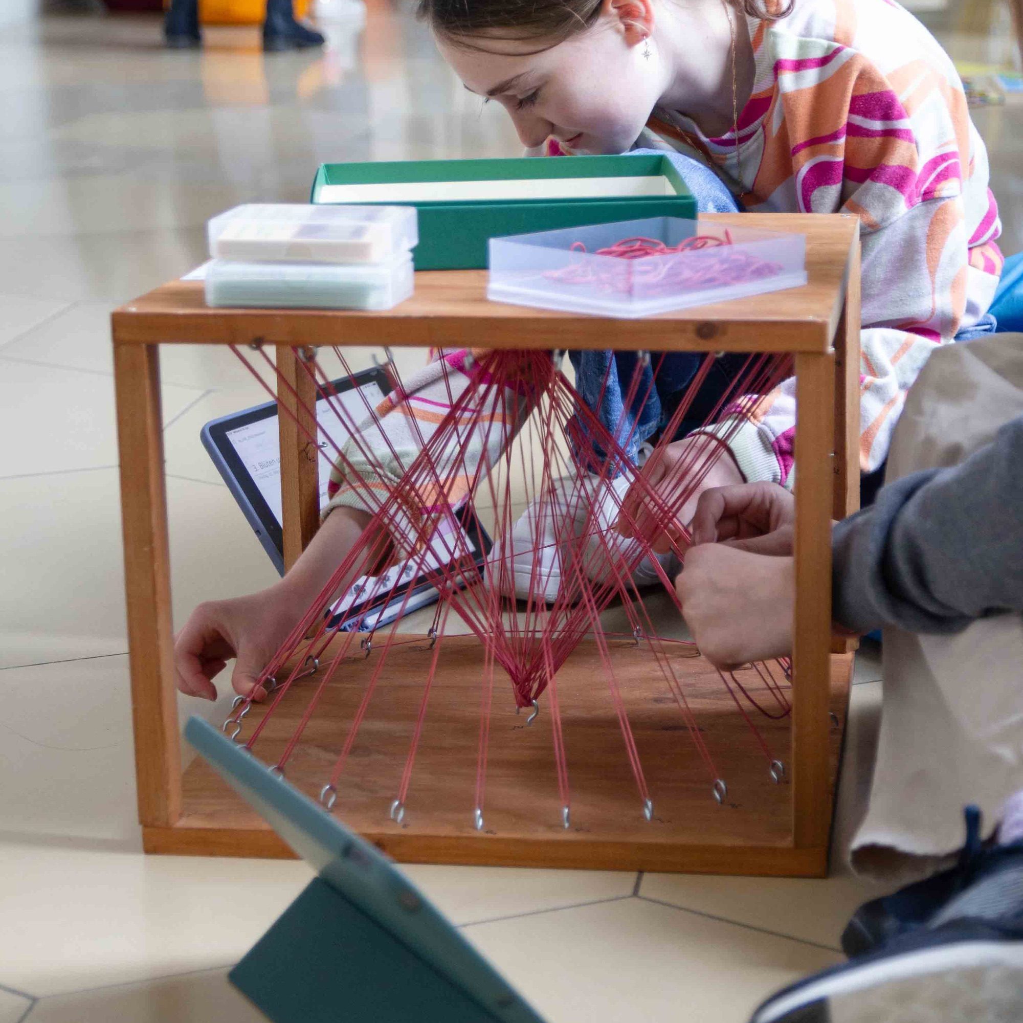Schülerinnen spannen Fäden in einem Holzrahmen beim praktischen Lernen, Maria-Ward-Realschule Neuburg